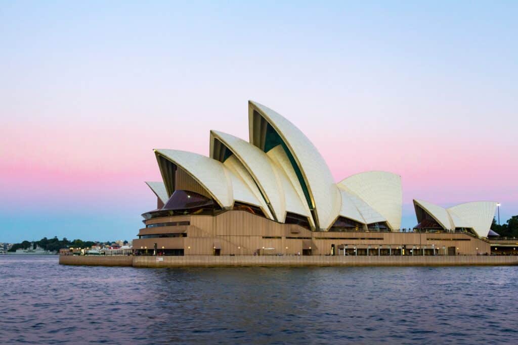 The photo shows one side of the Sydney Opera House in Australia, under a pretty pink sky.