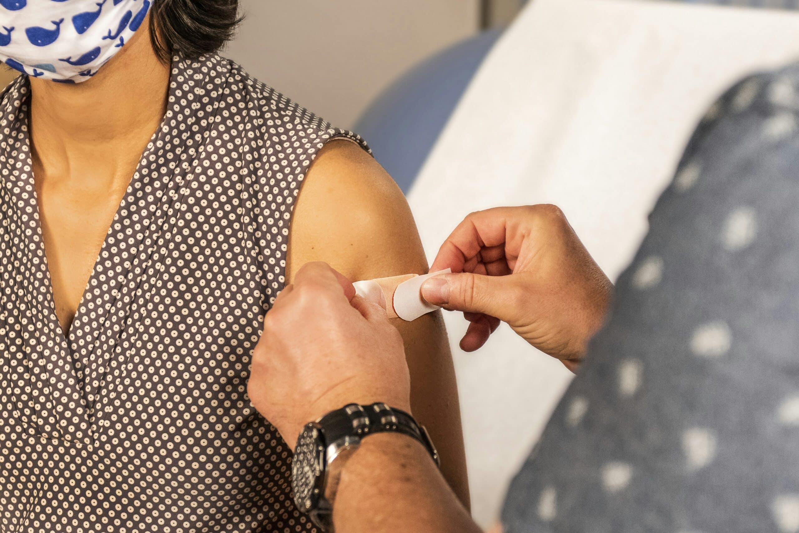 A doctor puts a bandage on the arm of a woman who has just been vaccinated.