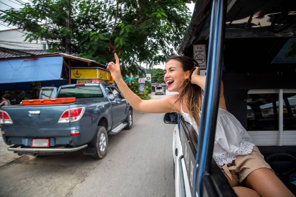 Smiling young woman waving to someone from a taxi in Indonesia.