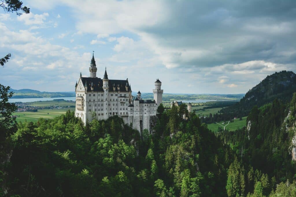 Photo of Neuschwanstein castle in Germany in a rural setting under a clear sky.