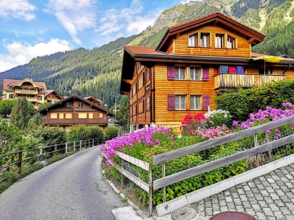 Typical Swiss wooden house on the edge of a flower-filled road.