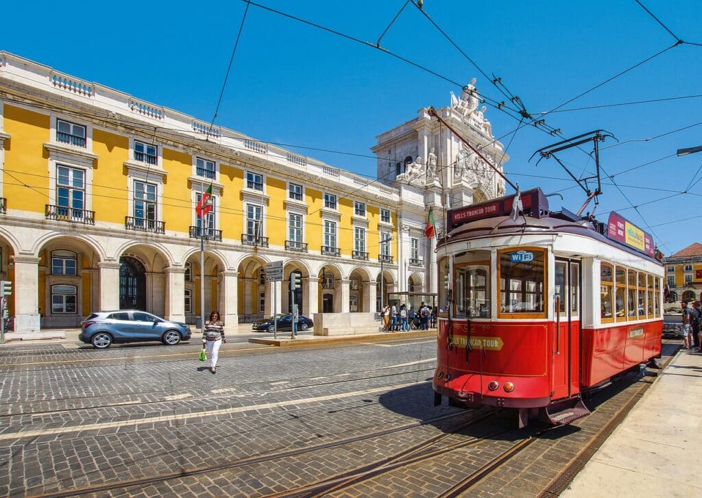 Lisbon streetcar running in front of an ornately decorated building with a yellow facade.