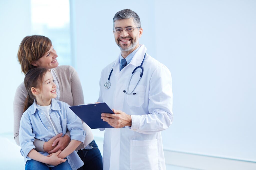 Doctor showing a medical report to a woman and her child. Everyone is smiling and in good spirits.