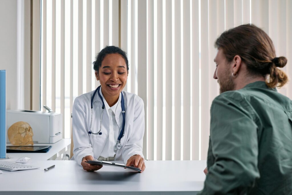 A young doctor discusses her diagnosis with her patient. They are both smiling and confident about their diagnosis.